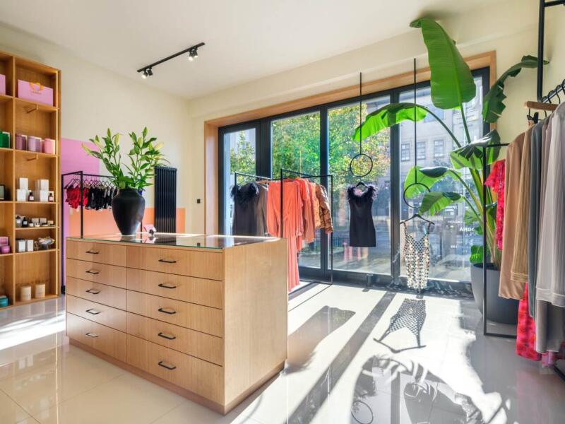 Butik z modnymi ubraniami, roślinami i drewnianymi meblami.