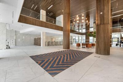 Nowoczesne lobby z drewnianymi filarami i geometrycznym dywanem.