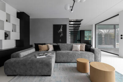 Nowoczesny salon z szarą sofą i designerskimi dodatkami.