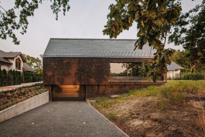 Nowoczesny dom z cegły w otoczeniu drzew, minimalistyczna architektura.