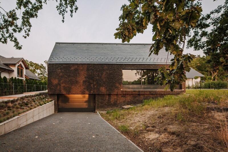 Nowoczesny dom z cegły w otoczeniu drzew, minimalistyczna architektura.