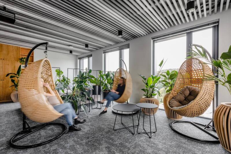 Nowoczesny salon z wiszącymi fotelami i zielenią.