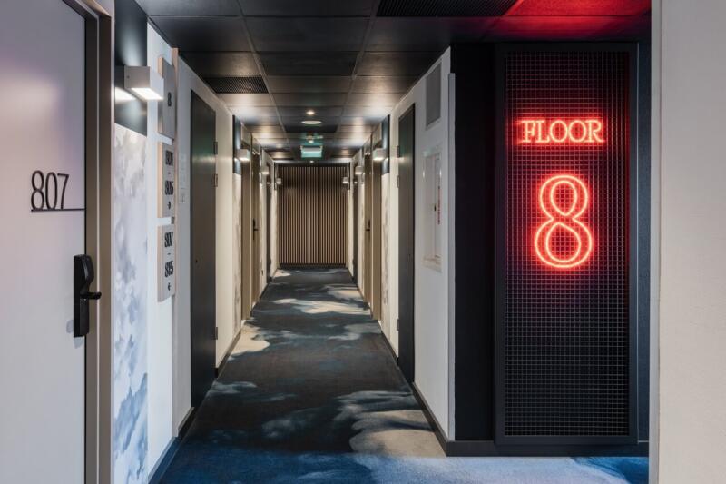 Korytarz hotelowy z neonem Floor 8. Nowoczesny design z klasą.