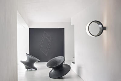 Nowoczesne krzesła designerskie i geometryczna ściana w minimalistycznym wnętrzu.