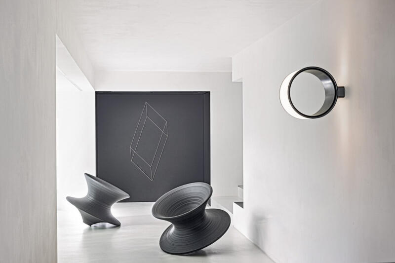 Nowoczesne krzesła designerskie i geometryczna ściana w minimalistycznym wnętrzu.