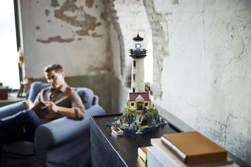 Model latarni morskiej w industrialnym wnętrzu z mężczyzną na fotelu.