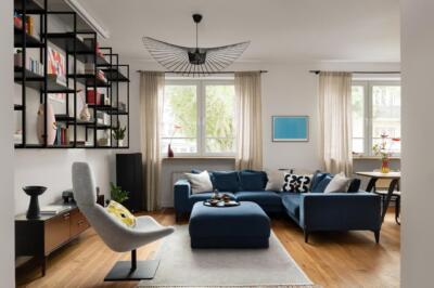 Nowoczesny salon z niebieską sofą i designerskim oświetleniem.