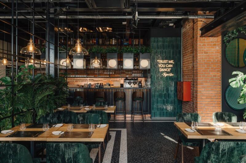 Stylowy bar z zielonymi akcentami i nowoczesnym oświetleniem.