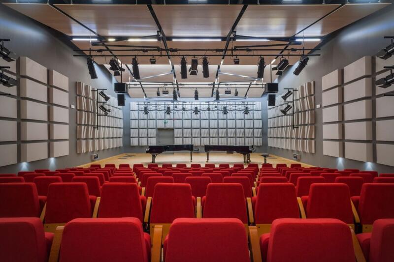 Sala koncertowa z czerwonymi fotelami i akustycznymi panelami. Idealna przestrzeń do muzyki.