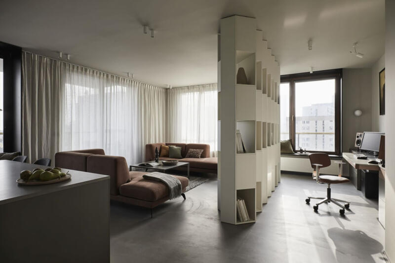 Przestronny salon z nowoczesnymi meblami i minimalistyczną biblioteczką.
