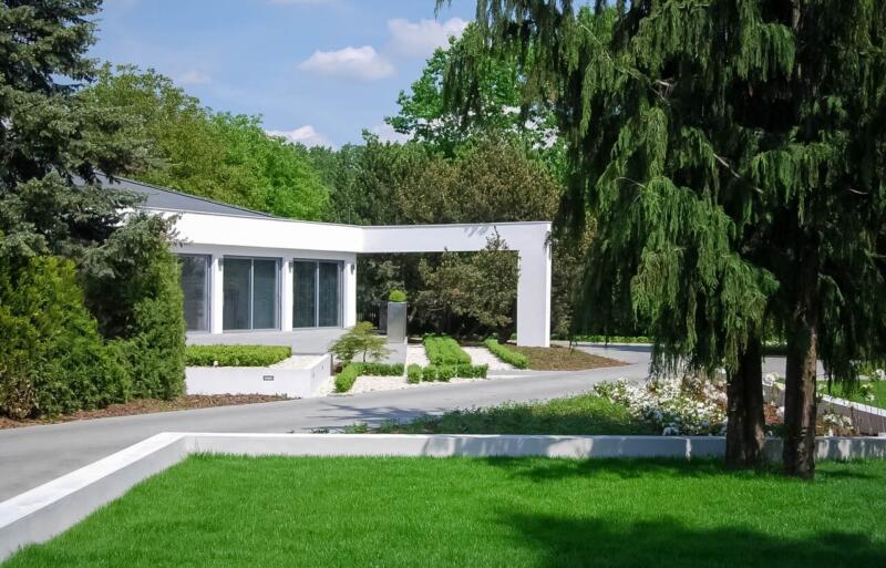 Nowoczesny dom otoczony zielenią, minimalistyczna architektura.