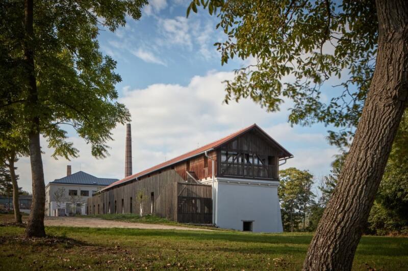 Przebudowany budynek w zielonym otoczeniu, nowoczesna architektura.