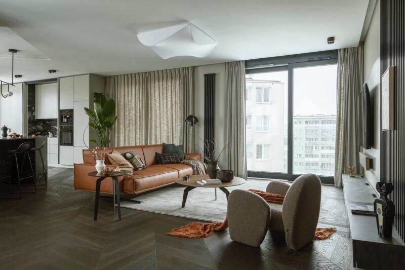 Nowoczesny salon z brązową sofą i eleganckimi dodatkami.
