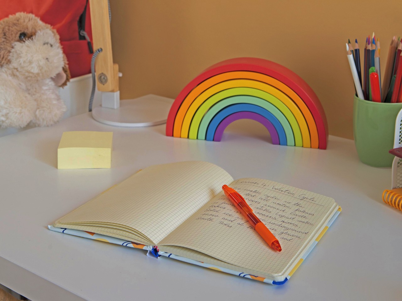 Notebook na biurku z kolorową tęczą i kredek zestawem.