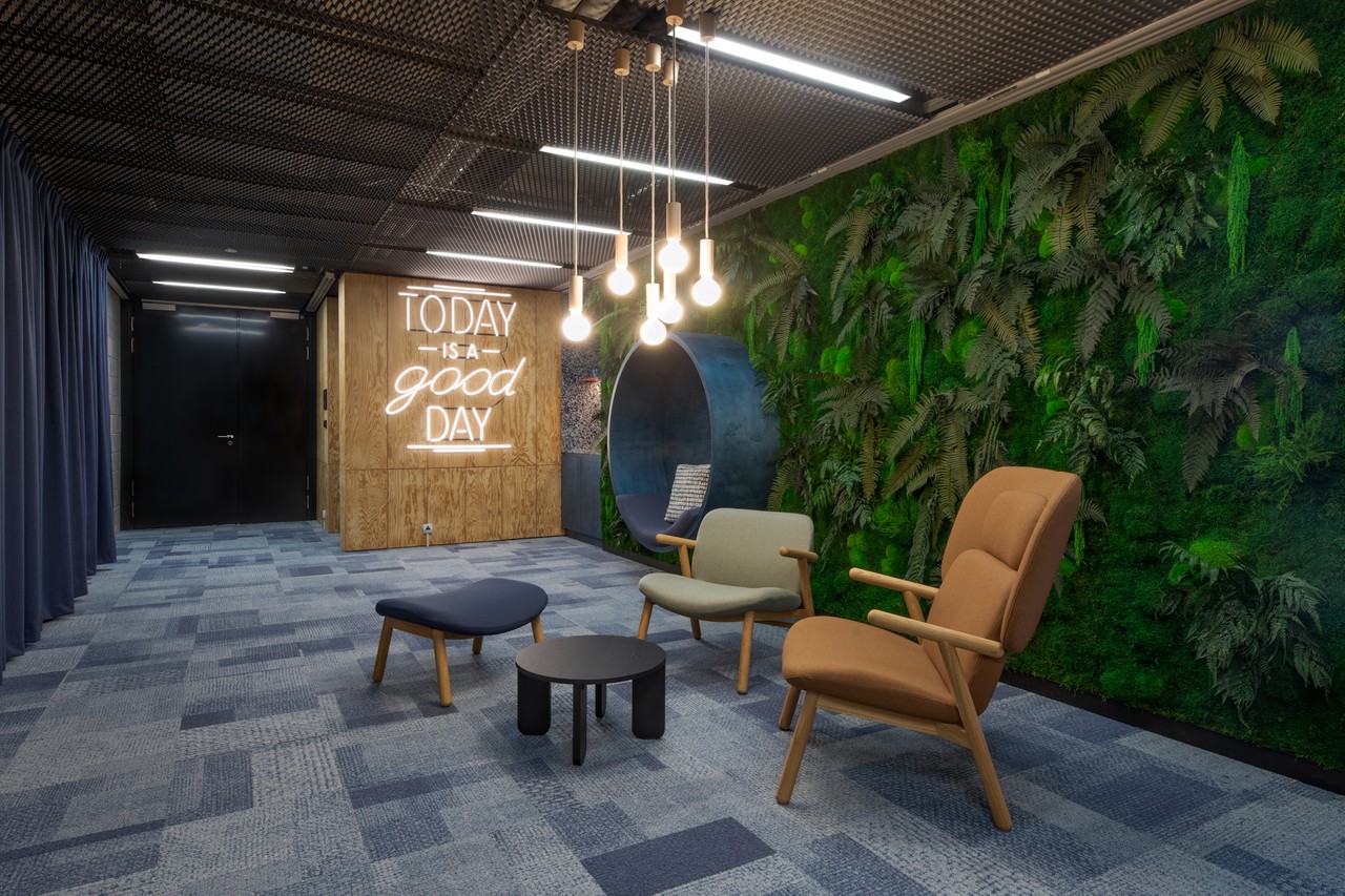 Współczesna przestrzeń relaksu z zieloną ścianą i designerskimi fotelami.