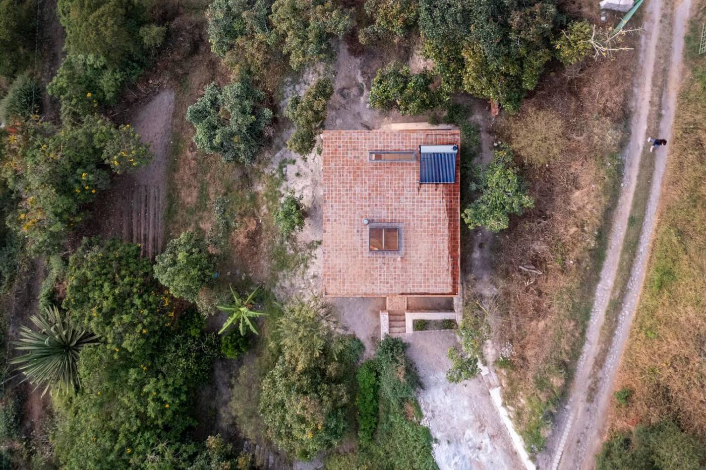 Dom z ceglaną dachówką, otoczony zielenią, widok z lotu ptaka.