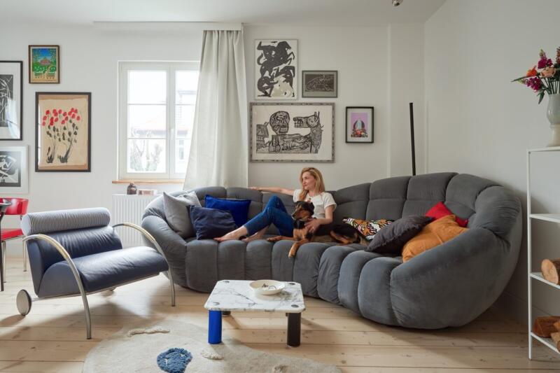 Nowoczesny salon z designerską sofą, obrazami i stylowym krzesłem.