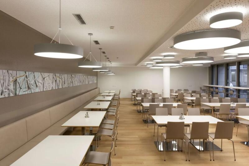 Nowoczesna stołówka z designerskim oświetleniem i drewnianą podłogą.