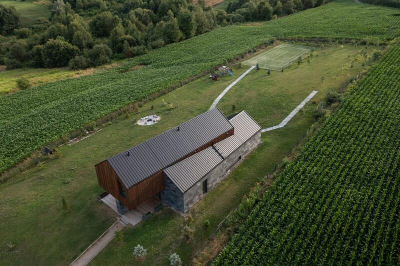 Nowoczesny dom w otoczeniu zielonych pól i przestrzeni rekreacyjnej.