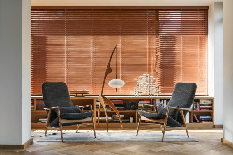 Przytulny salon z designerskimi fotelami i drewnianymi żaluzjami. Cudownie!
