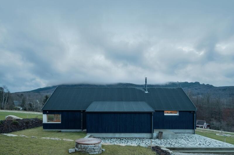 Czarny dom na tle gór, nowoczesna architektura minimalistyczna.
