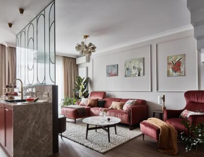 Elegancki salon z bordową kanapą, nowoczesnym dekoracyjnym oświetleniem.