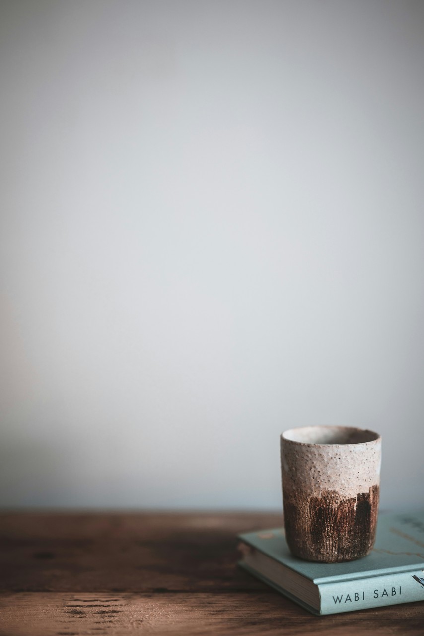 Ceramiczny kubek na książce, minimalistyczny styl Wabi-Sabi.
