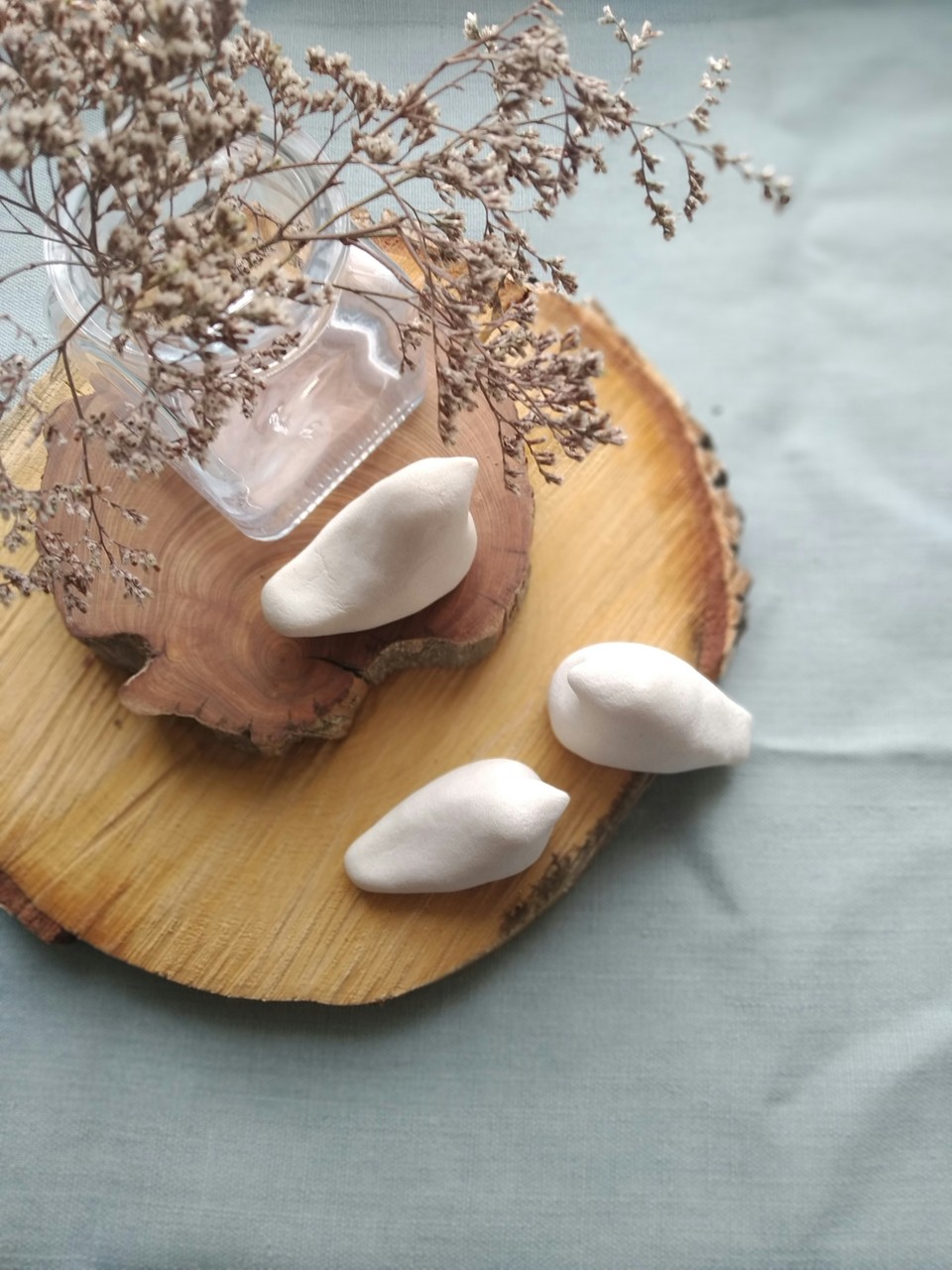 Drewniana podstawka, dekoracyjne gałązki i ceramiczne ozdoby.
