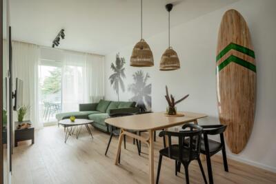 Współczesny salon z zieloną kanapą i dekoracją w stylu boho.