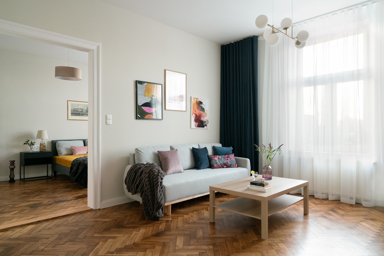 Salon z jasną sofą, poduszkami i drewnianą podłogą.