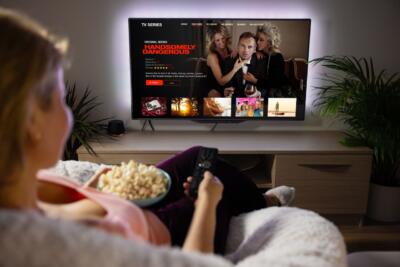 Kobieta z popcornem ogląda telewizję w przytulnym salonie. Relaks, prawda?