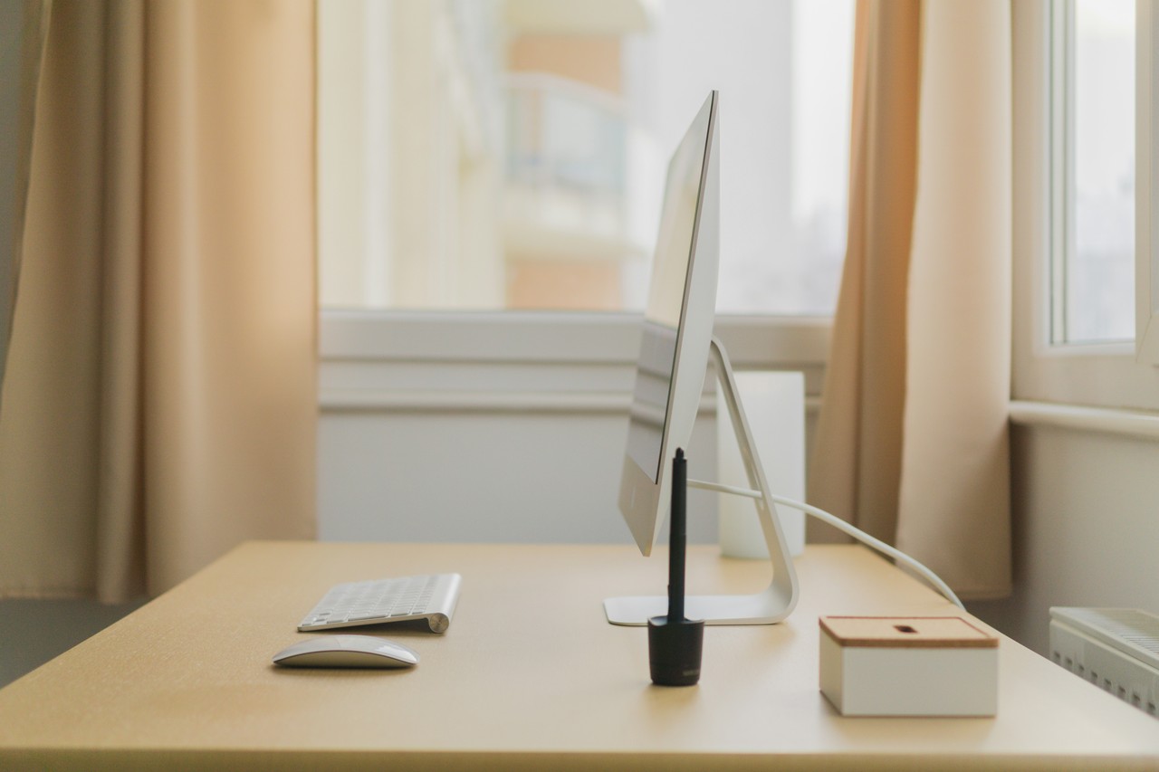 Minimalistyczne biuro: elegancki monitor, klawiatura i pióro.
