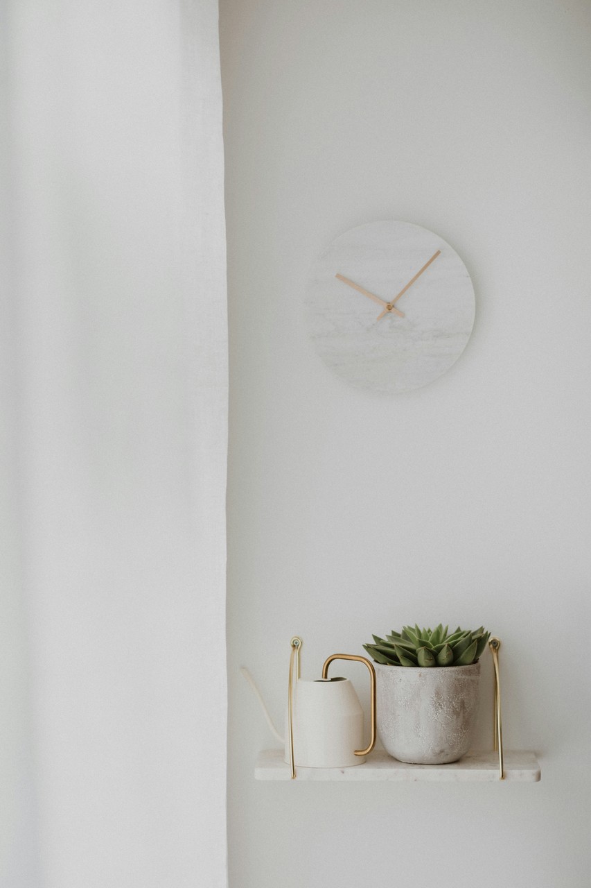 Elegancka półka z zegarem i kwiatem w stylu minimalistycznym.
