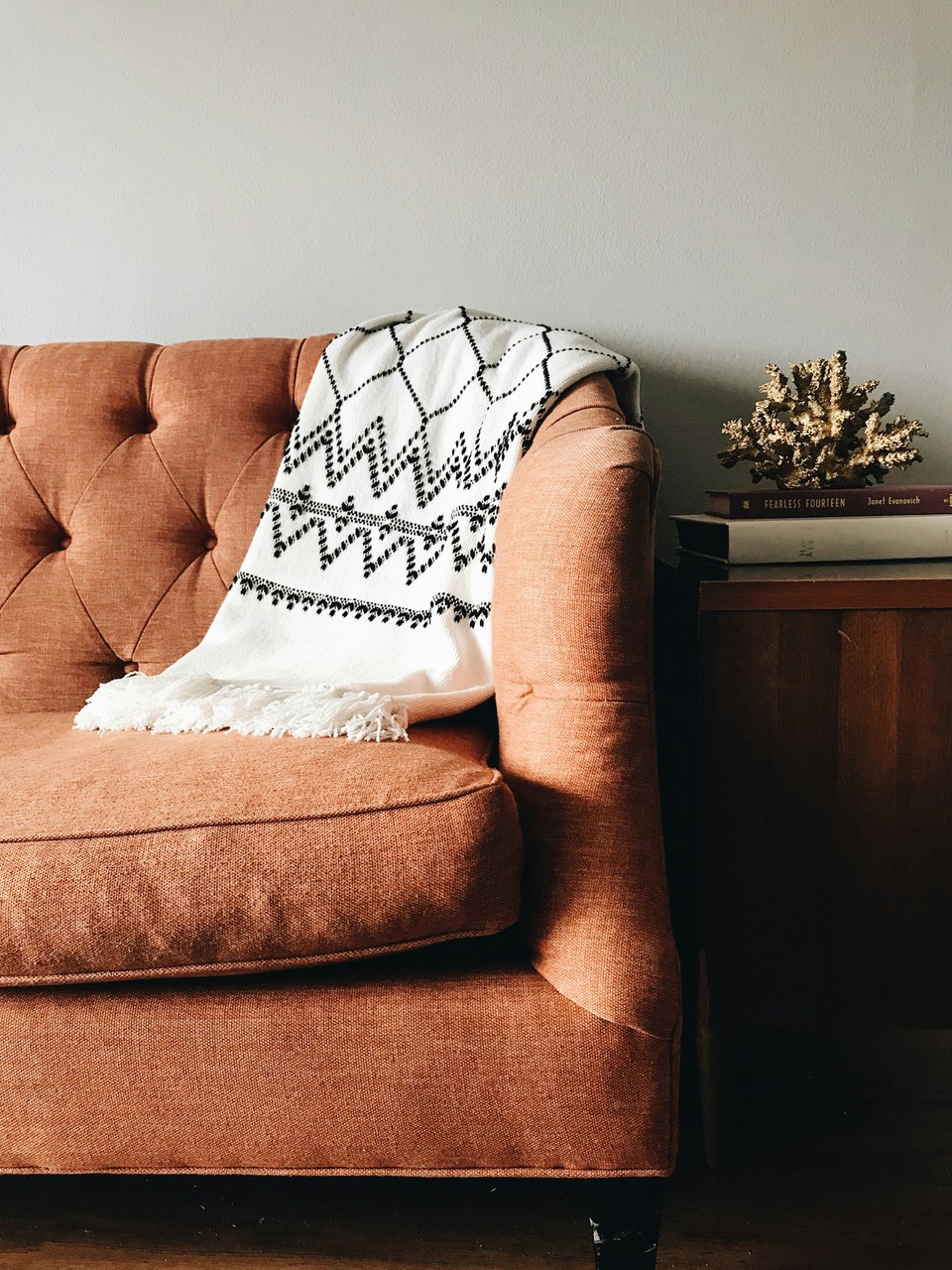 Brązowa sofa w stylu retro z dekoracyjnym pledem i książkami.