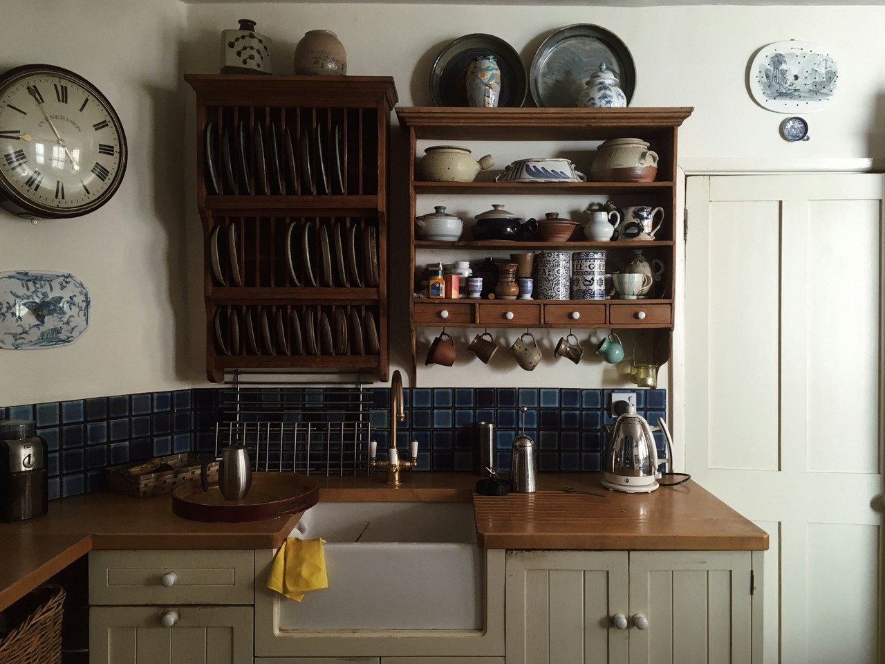Rustykalna kuchnia z drewnianymi półkami i porcelaną na półkach.
