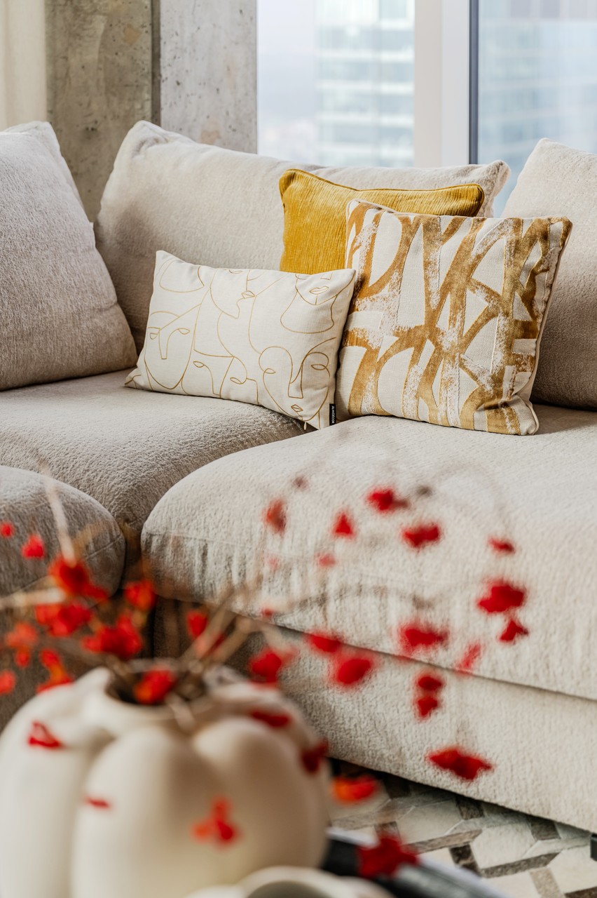 Szykowna kanapa z designerskimi poduszkami w jasnym salonie.