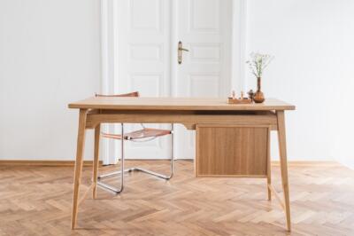 Drewniane biurko minimalistyczne na parkiecie z modnym fotelem.
