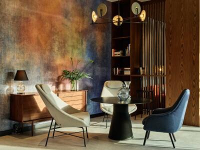 Przytulny salon z designerskimi fotelami i kolorową ścianą.