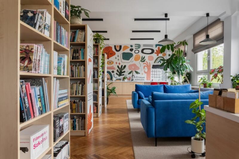 Nowoczesny salon z niebieskimi kanapami i kolorową ścianą.