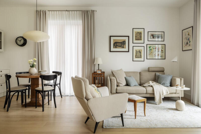 Przytulny salon z beżową sofą, drewnianym stołem i eleganckimi obrazami.