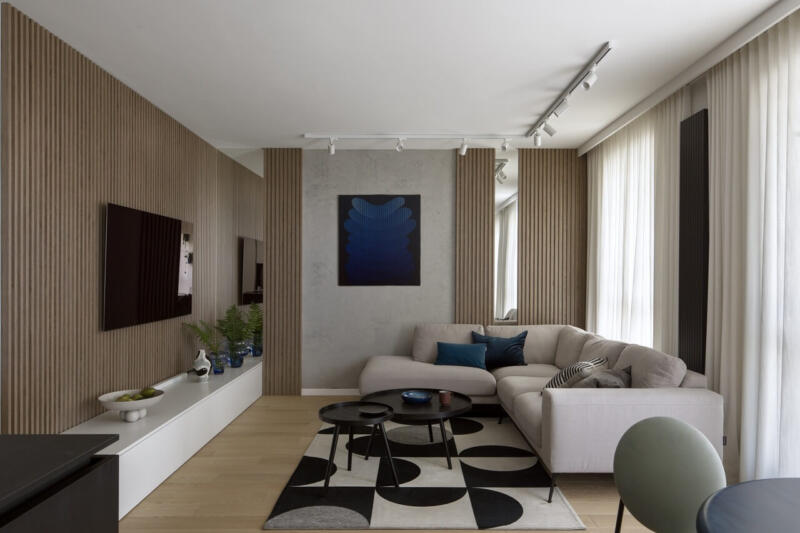 Elegancki salon z beżową sofą, geometrycznym dywanem i sztuką na ścianie.
