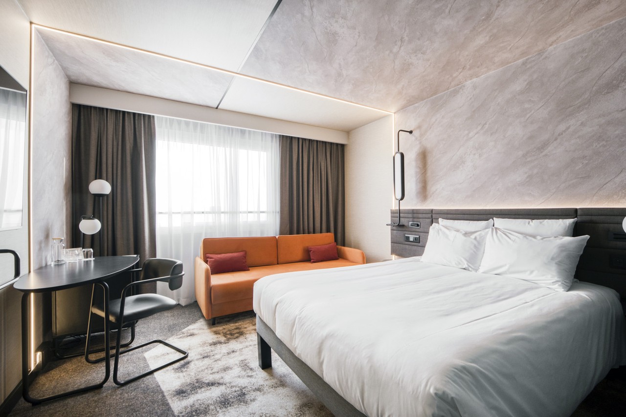 Nowoczesny pokój hotelowy z eleganckim wystrojem i jasnym oświetleniem.
