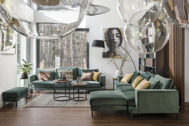 Nowoczesny salon z zieloną sofą i designerskimi dodatkami.