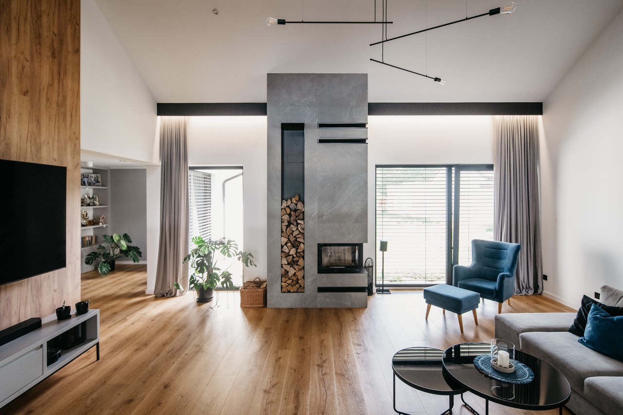 Elegancki salon z kominkiem, drewnianą podłogą i stylowym fotelem.