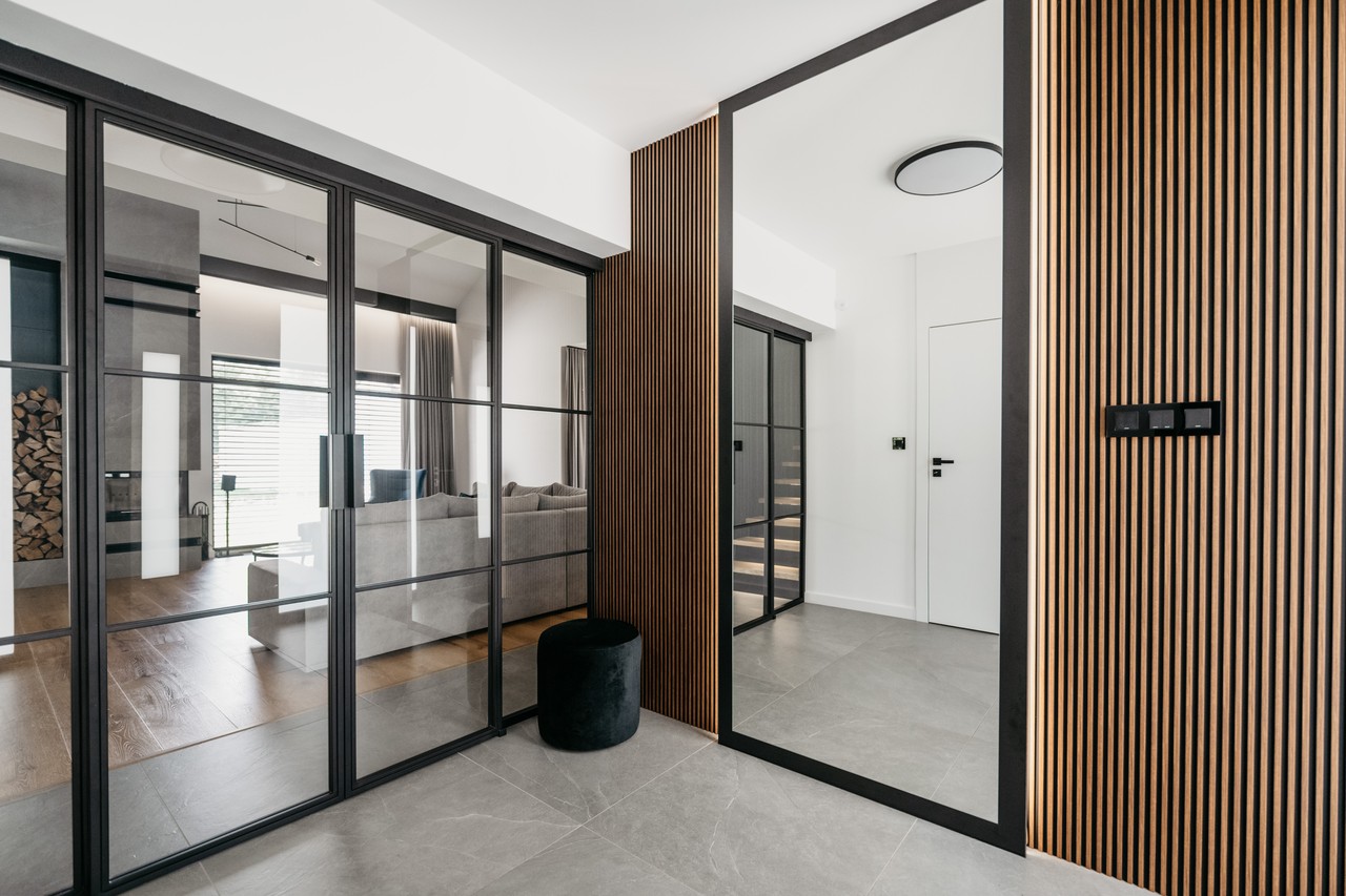 Elegancki salon z przeszklonymi drzwiami i drewnianą lamelą.