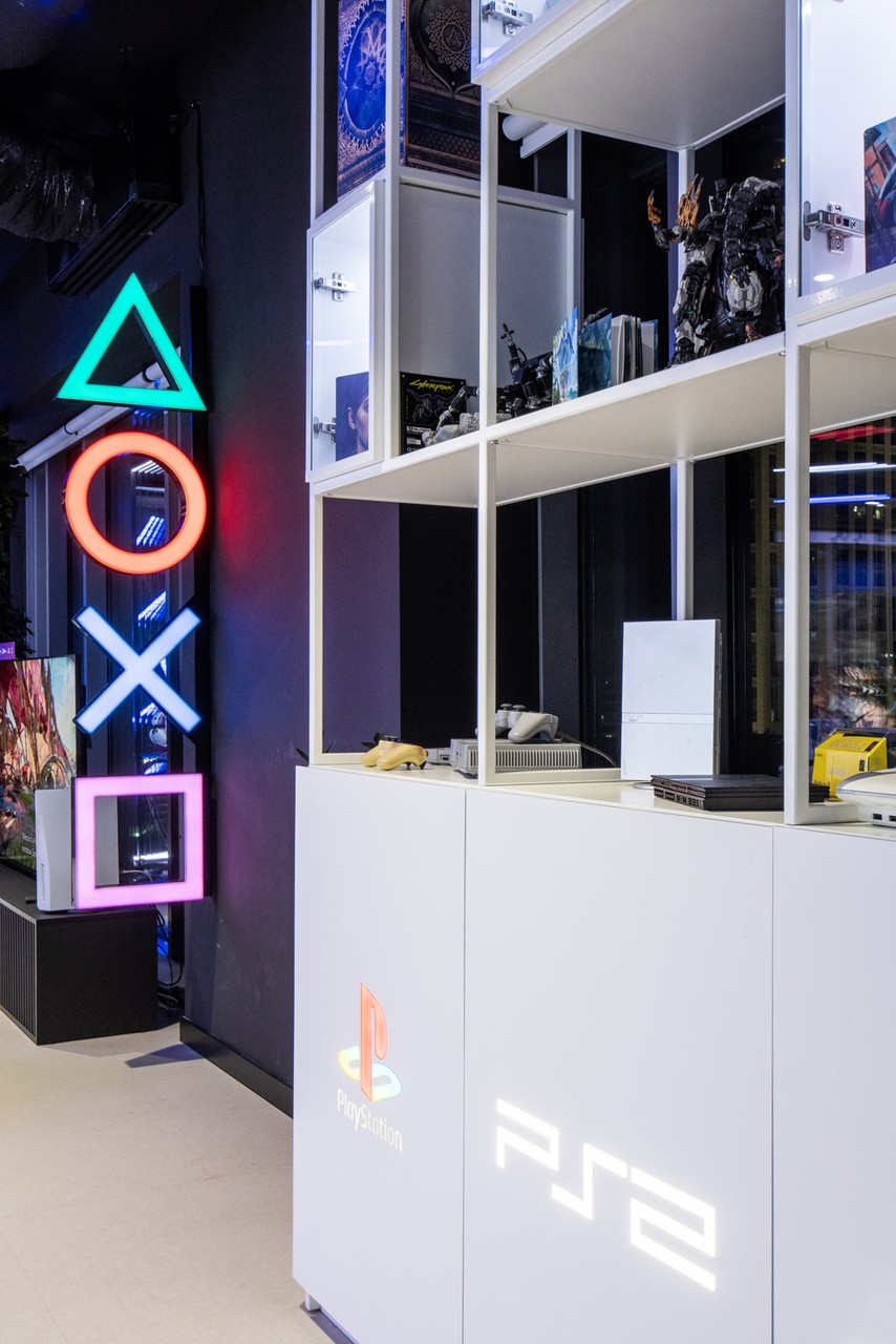 Neon PlayStation w nowoczesnym wnętrzu, designerskie półki.