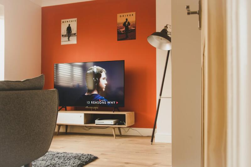 Nowoczesny salon z telewizorem na tle pomarańczowej ściany.