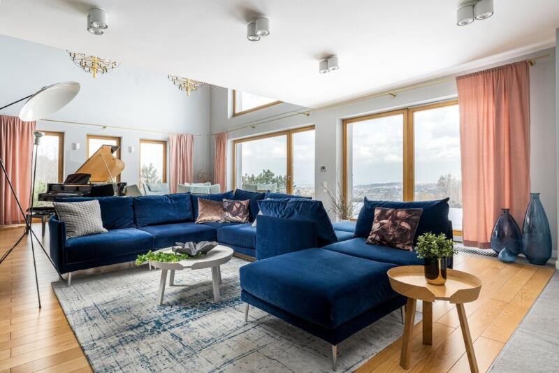 Przestronny salon z granatową sofą i wielkimi oknami.