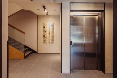 Nowoczesne lobby z elegancką windą i efektowną dekoracją ścienną.