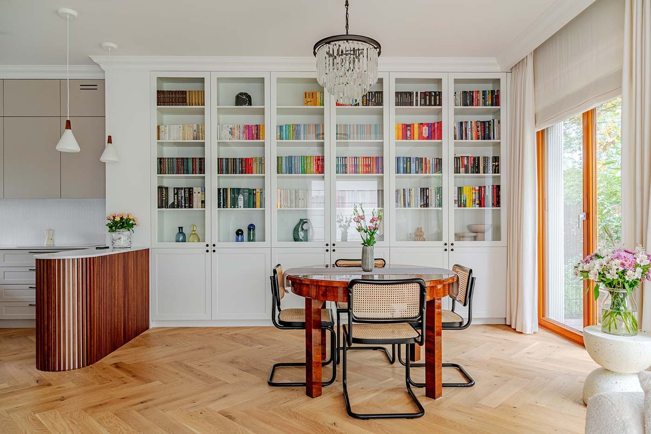 Elegancki salon z designerskimi meblami i przeszkloną biblioteczką.
